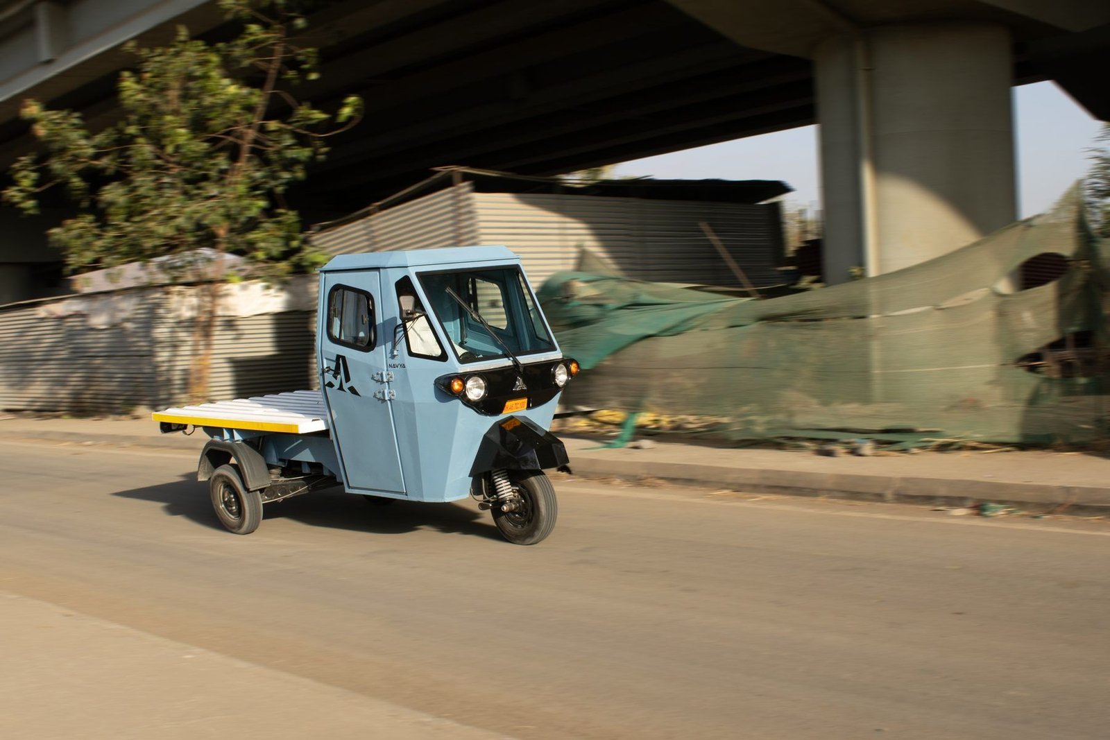 Front of the blue Navya with the finished headlight housing, on a flyover
