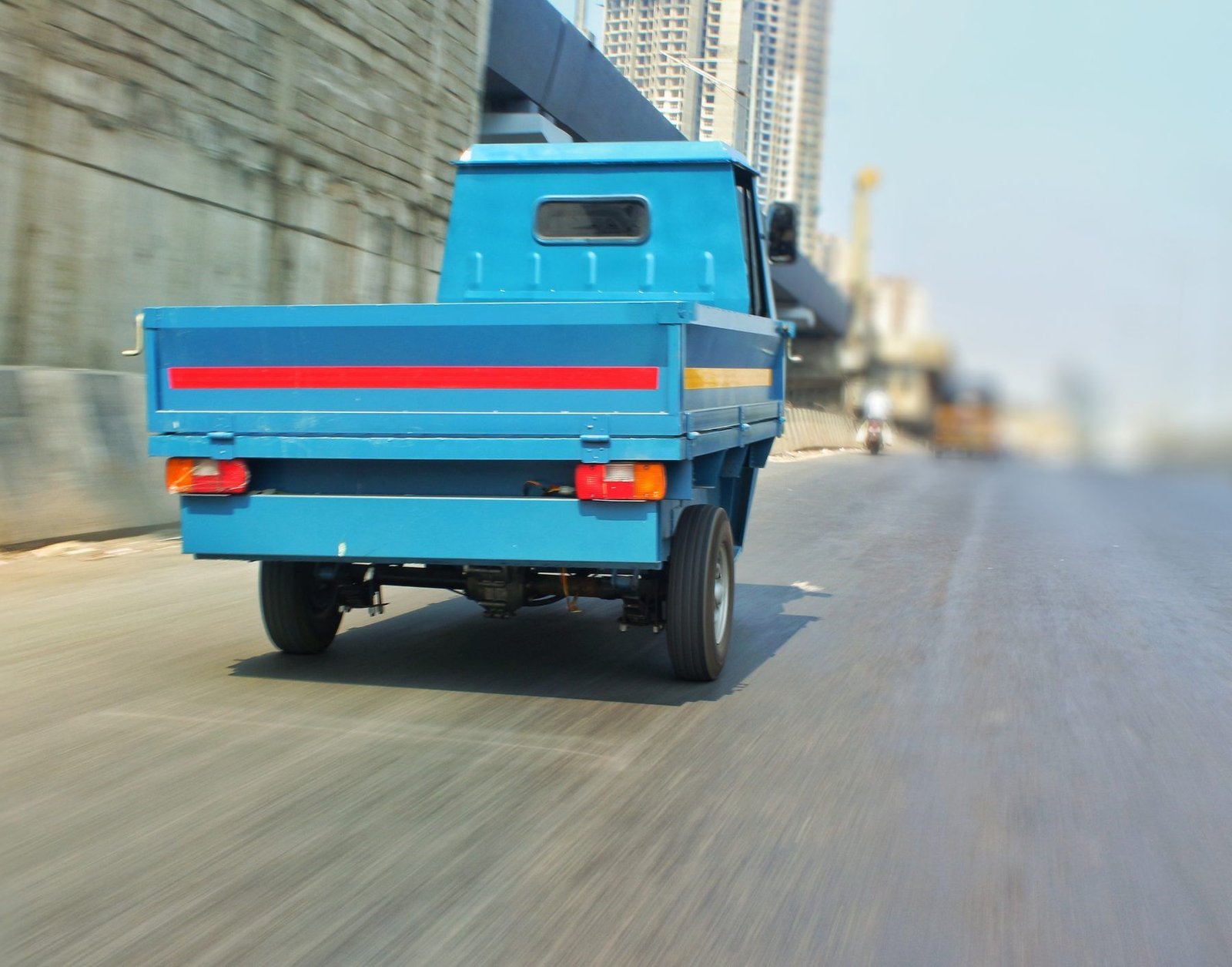 Rear view of a blue Navya with its flatbed, on the road