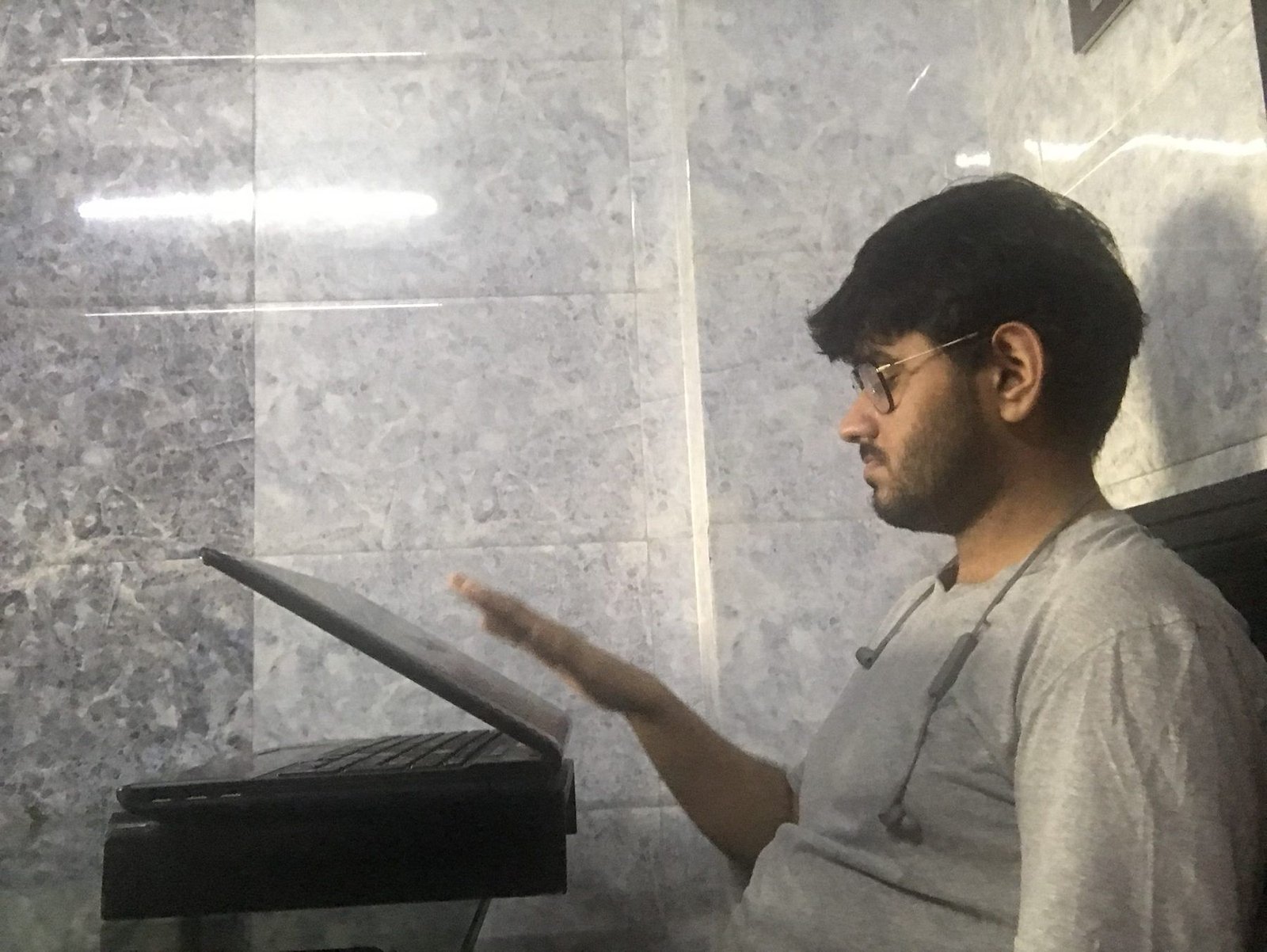 A person seated at the wall-mounted kiosk prototype, reaching for the tray